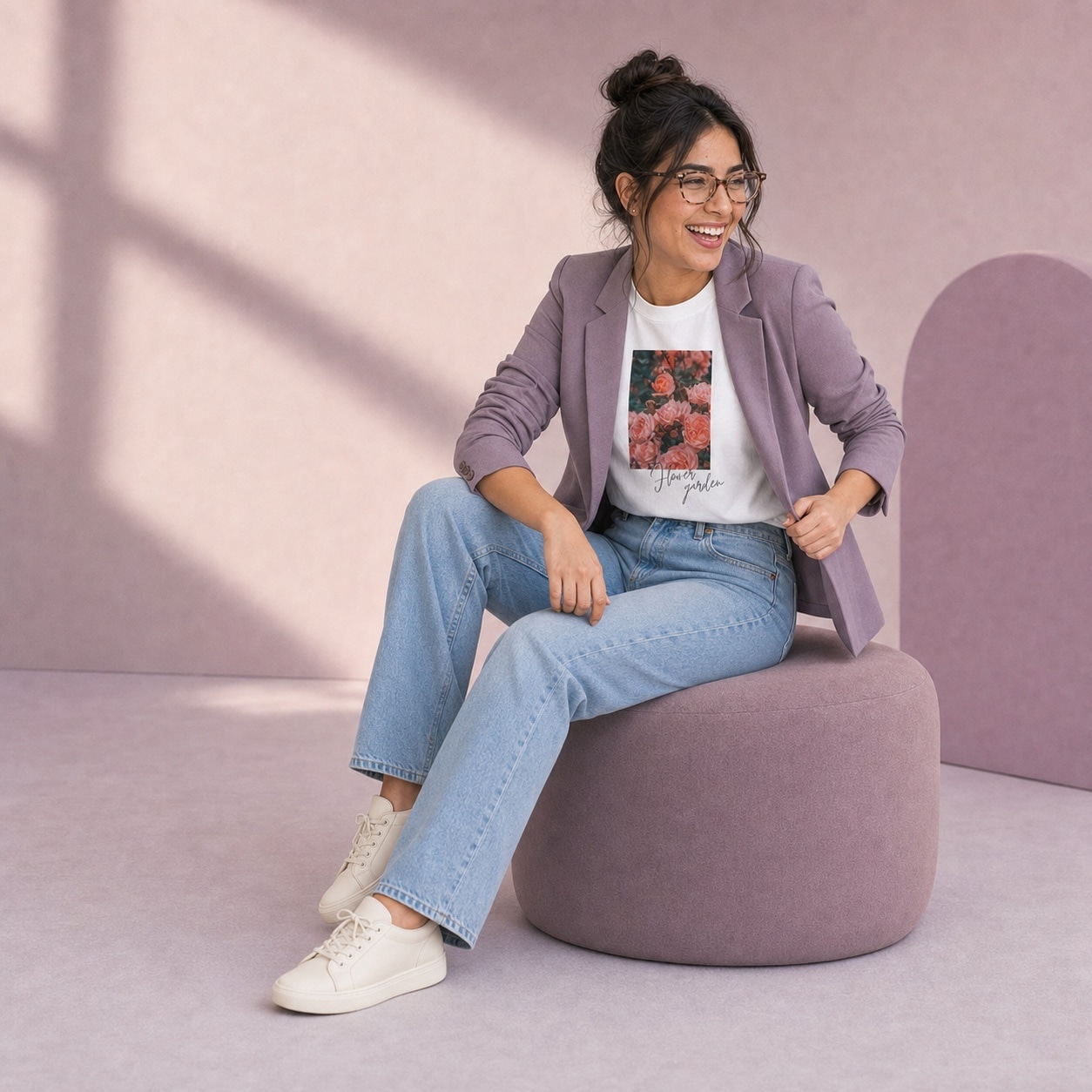 Modelo sonriendo en un pouf lila con la camiseta Flower garden